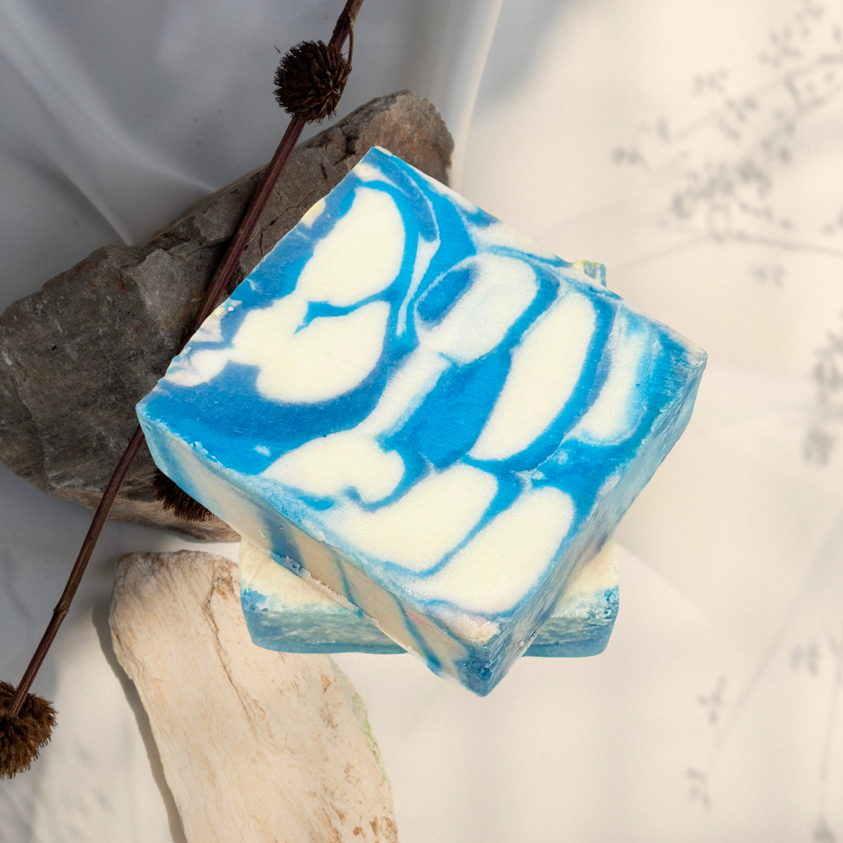 Blue and white swirled soap bar on a natural stone background