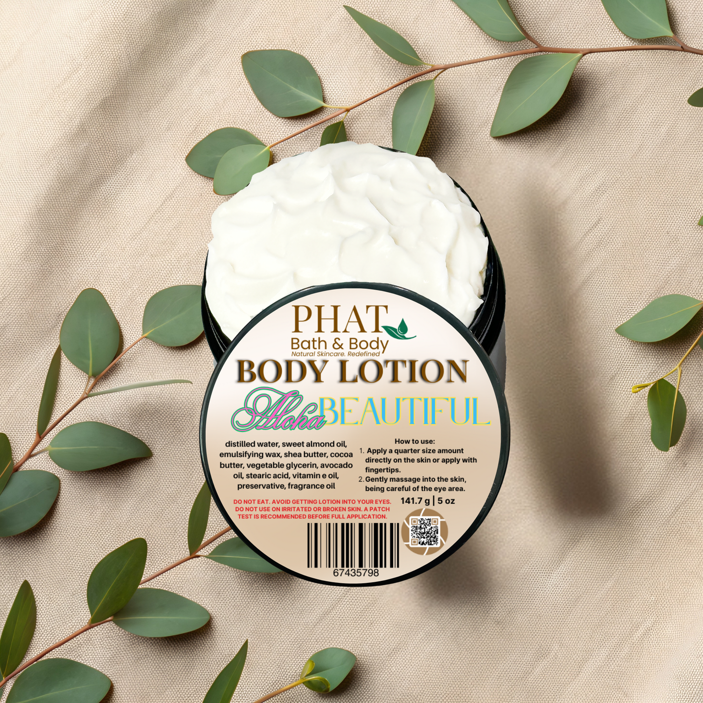 Body lotion container with 'PHAT Bath & Body' label on a beige fabric background with green leaves.