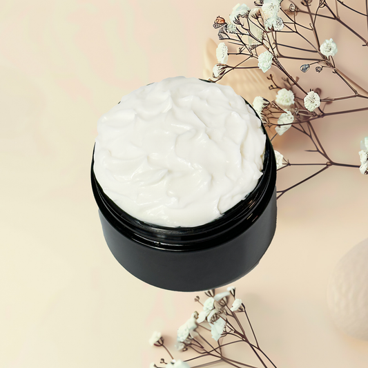 Black jar of white cream with dried flowers on a beige background