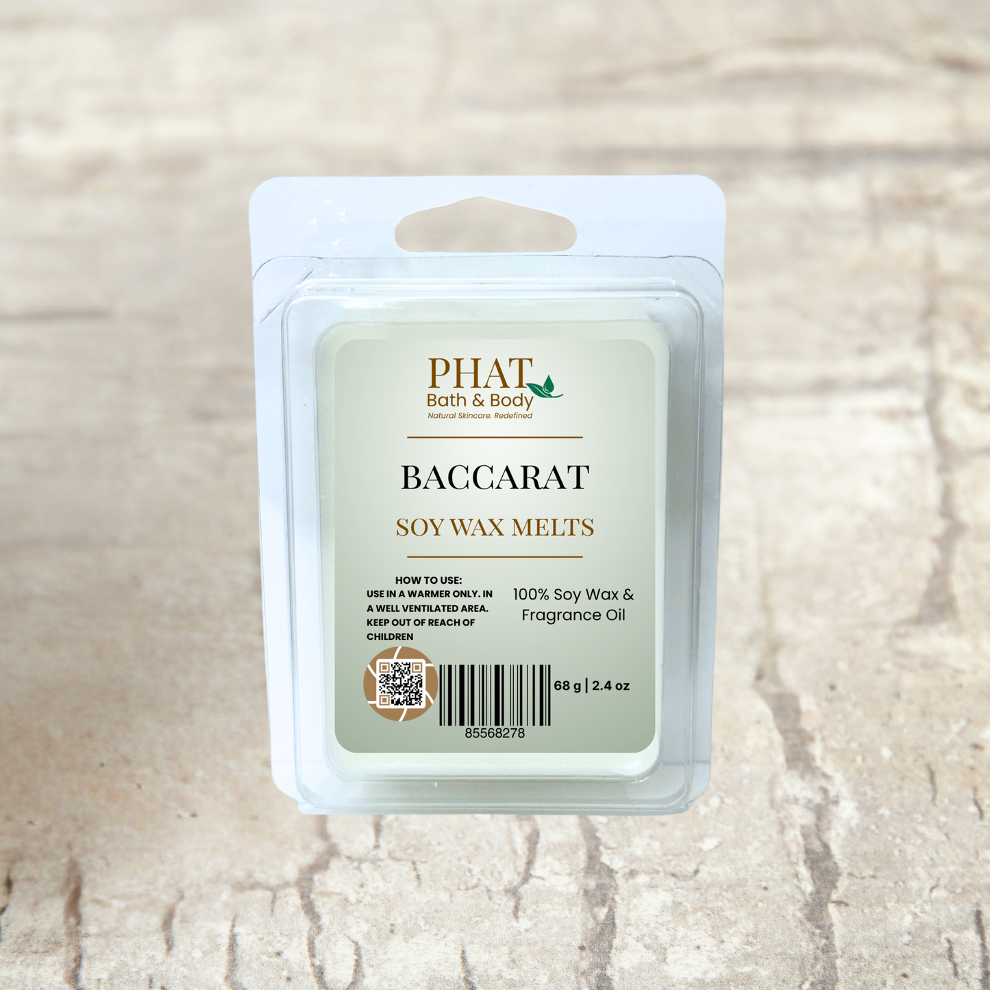 PHAT Bath & Body baccarat soy wax melts packaging on a beige fabric background with green leaves.