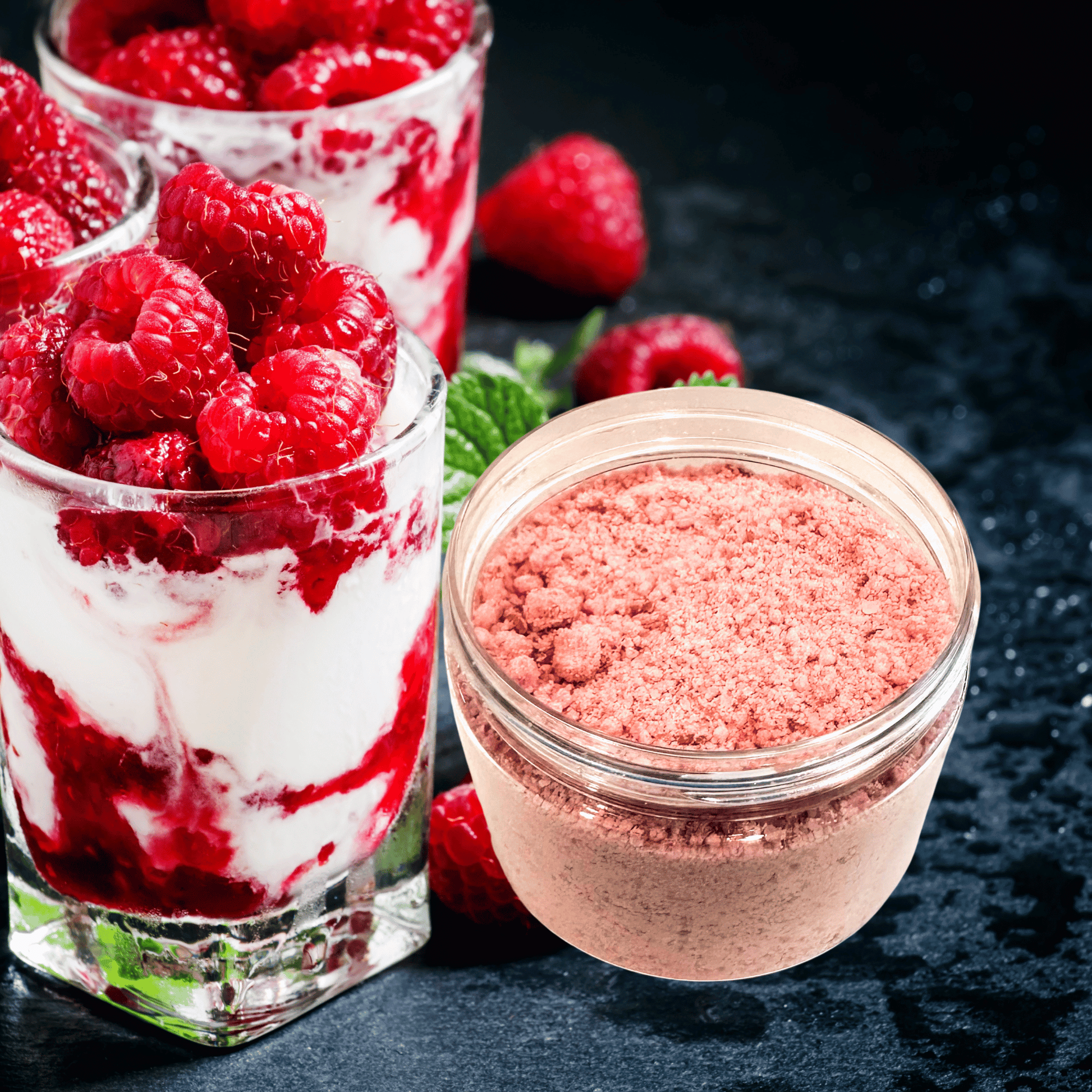 Jar of pink powder next to glasses filled with raspberries and cream on a dark surface