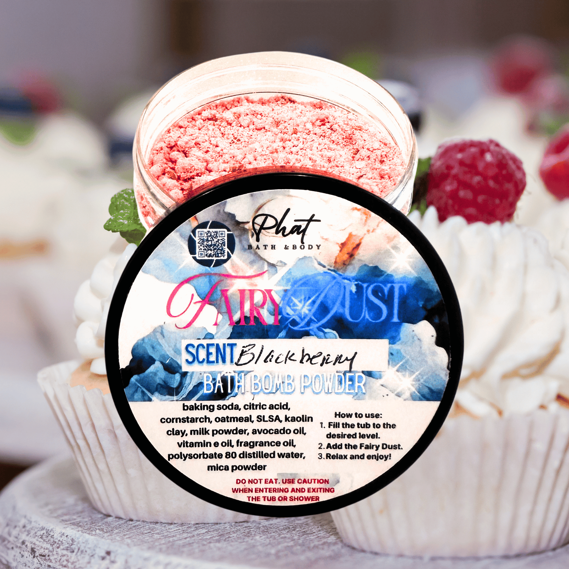 Bath bomb powder container with 'Fairy Dust' branding on a blurred background of cupcakes.