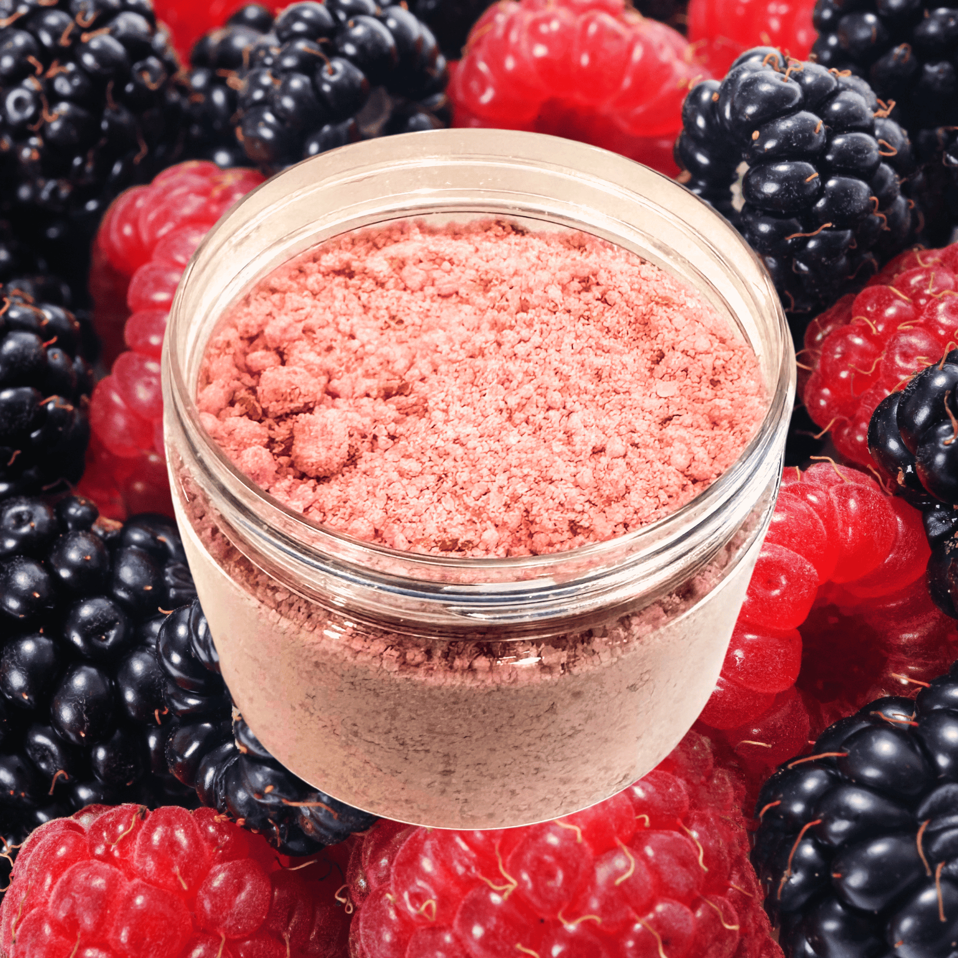 Jar of pink powder surrounded by blackberries and raspberries