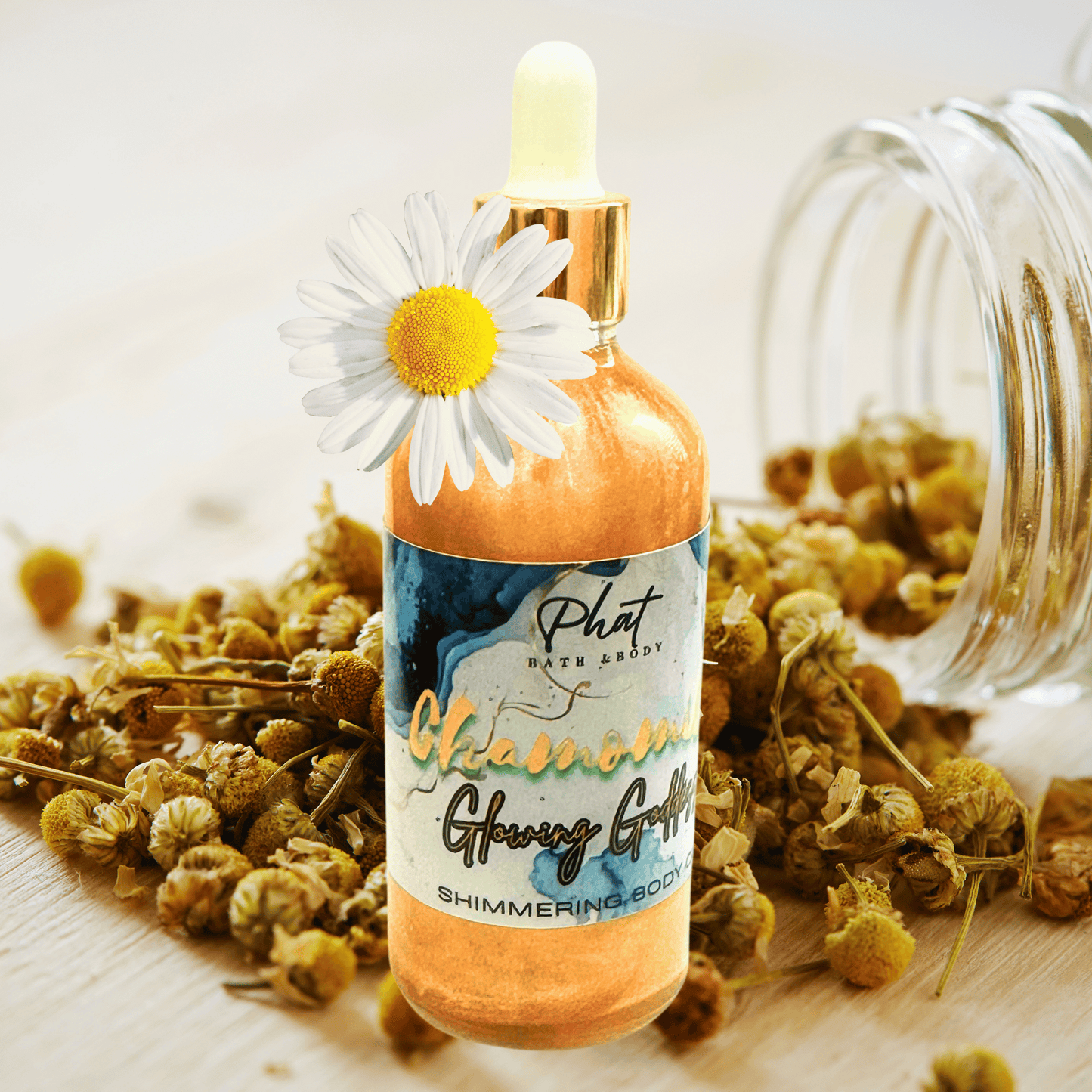 Bottle of 'Phat Bath Body' chamomile glowing griffin product with a dropper and a daisy on top, surrounded by dried flowers.