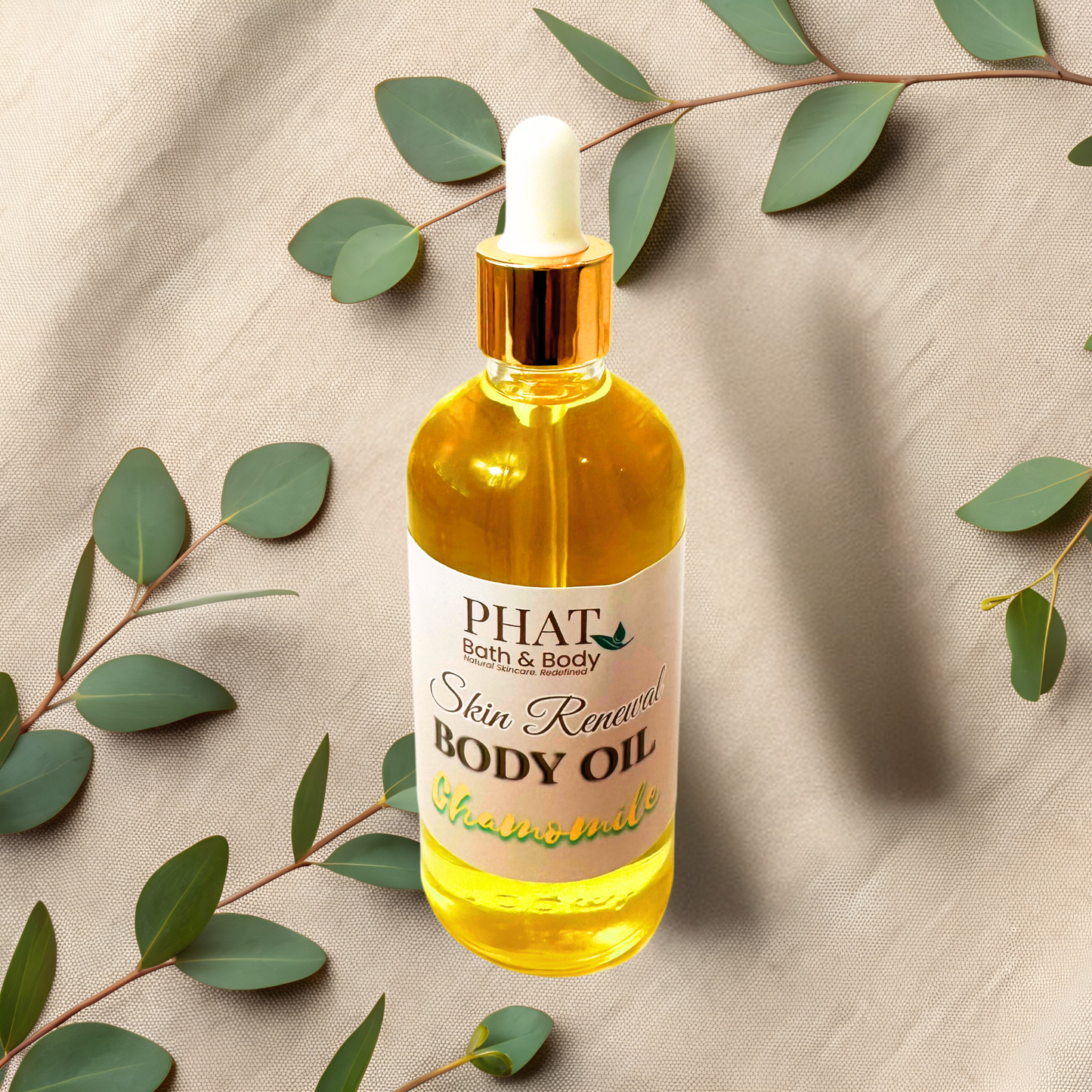 Bottle of PHAT Bath & Body Skin Renewal Body Oil with eucalyptus leaves on a beige fabric background