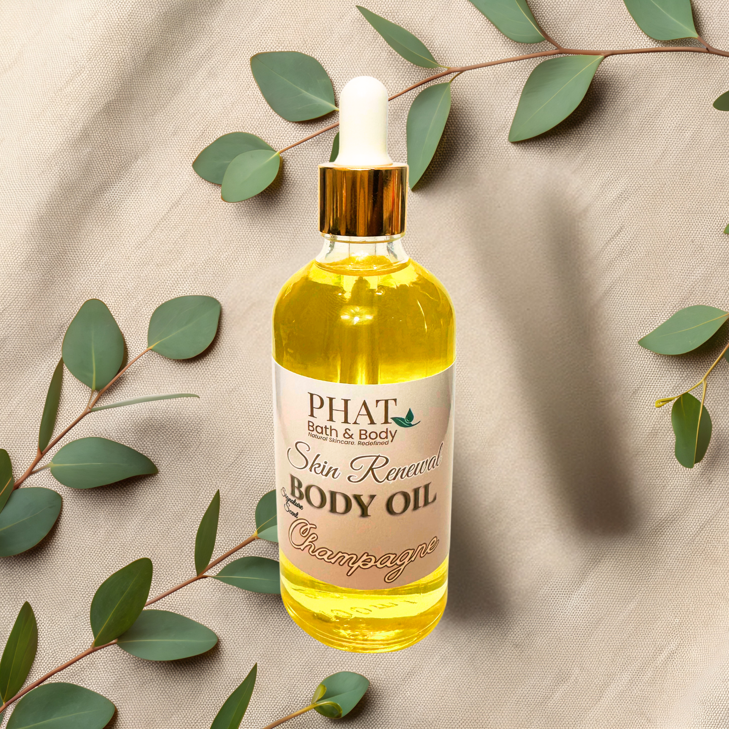 Bottle of Phat Bath & Body Skin Renewal Body Oil with a dropper on a beige fabric background with green leaves.