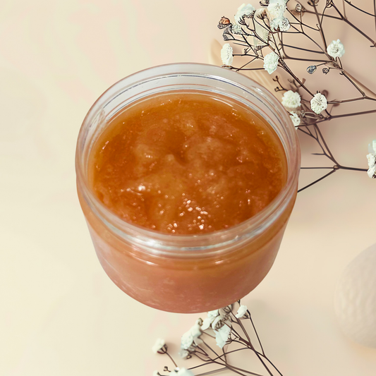 Jar of brown sugar scrub with white flowers on a beige background