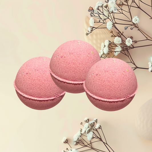 Three pink bath bombs with white flowers on a beige background