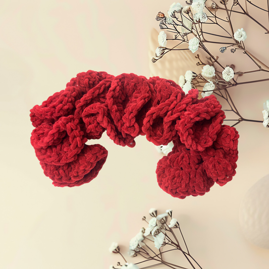 Red knitted headband on a light tan background with white flowers.