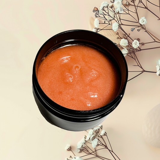Black container with red scrub on a beige background with white flowers