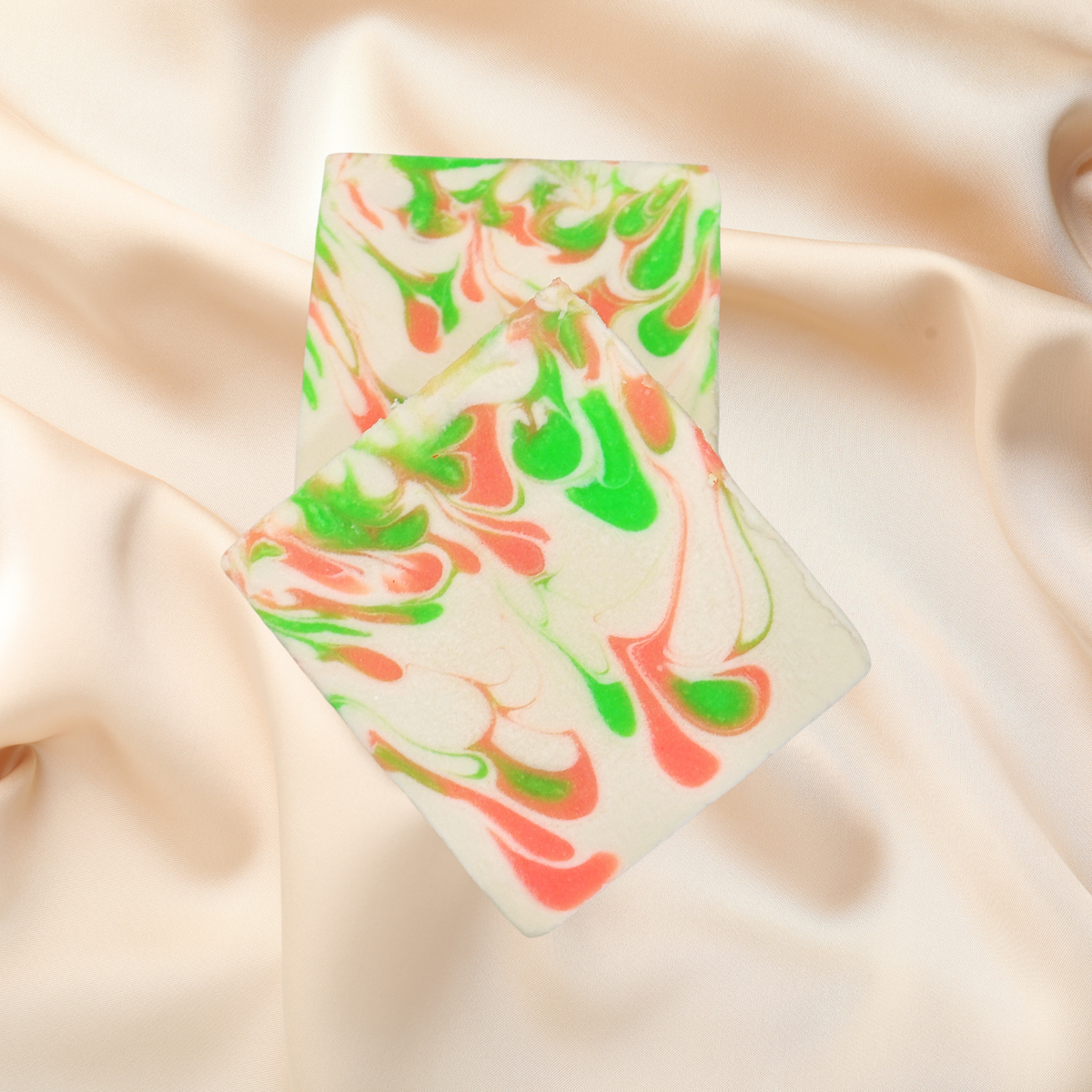 Marbled soap bar with green and pink swirls on a beige fabric background