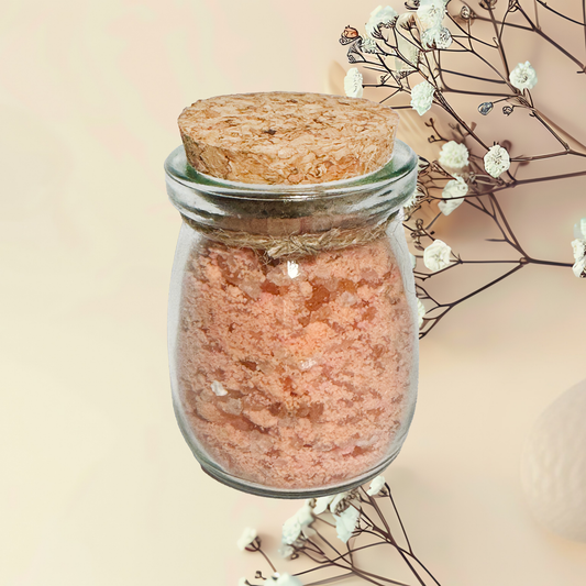 Glass jar with cork lid containing a pinkish substance, surrounded by white flowers and branches on a beige background.