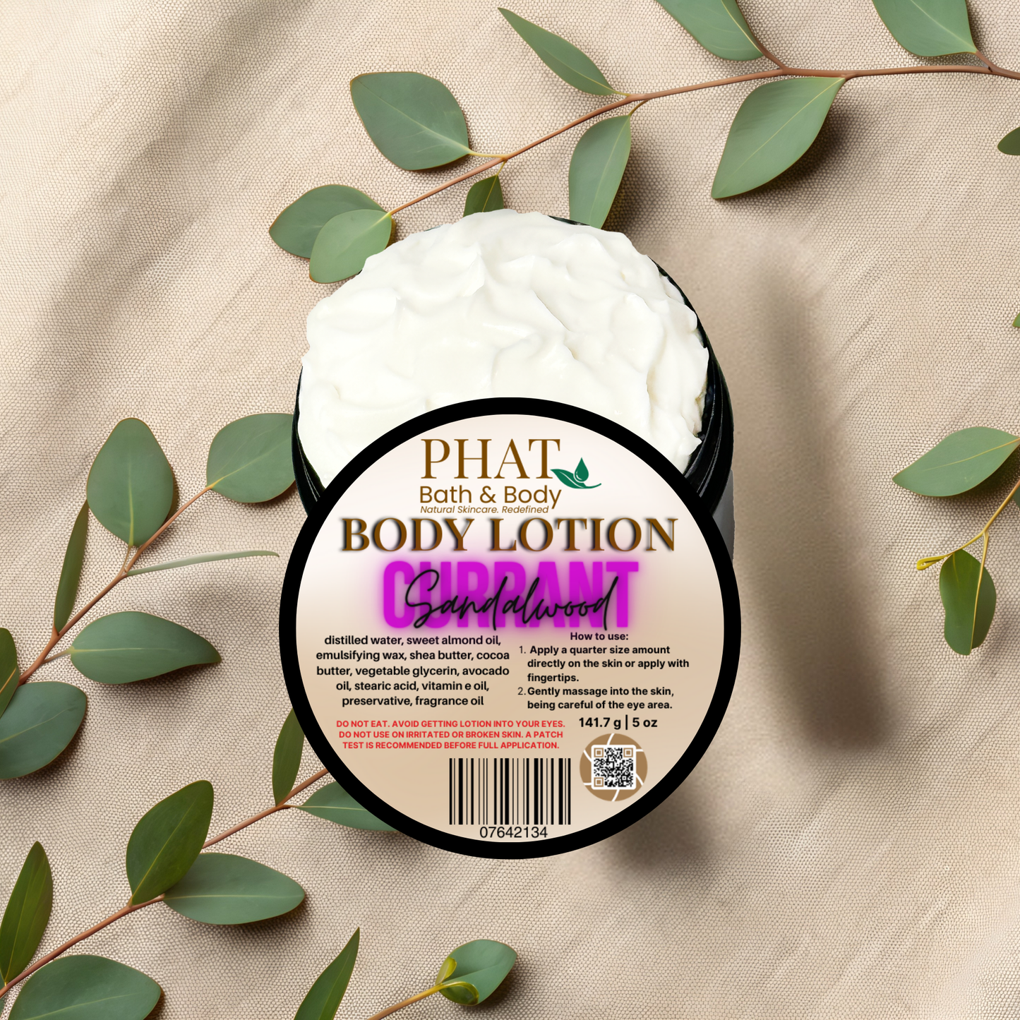 Body lotion container with 'Phat Bath & Body' branding on a beige fabric background with green leaves.