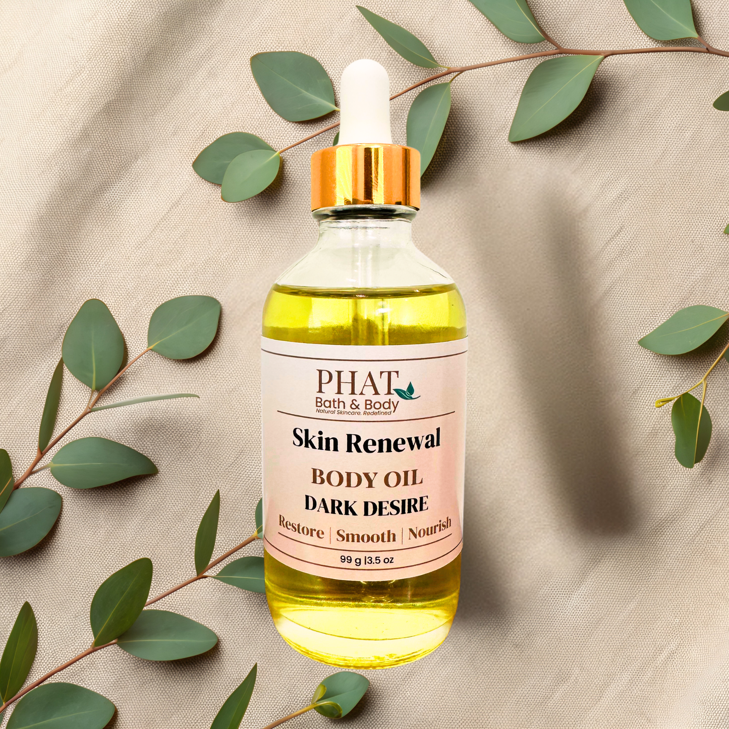 A bottle of PHAT Bath & Body 'Skin Renewal' body oil with a gold cap and white dropper, filled with yellow oil, styled on a beige fabric background with eucalyptus leaves.