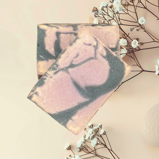 Marbled soap bar with pink and gray hues on a light background with small white flowers.