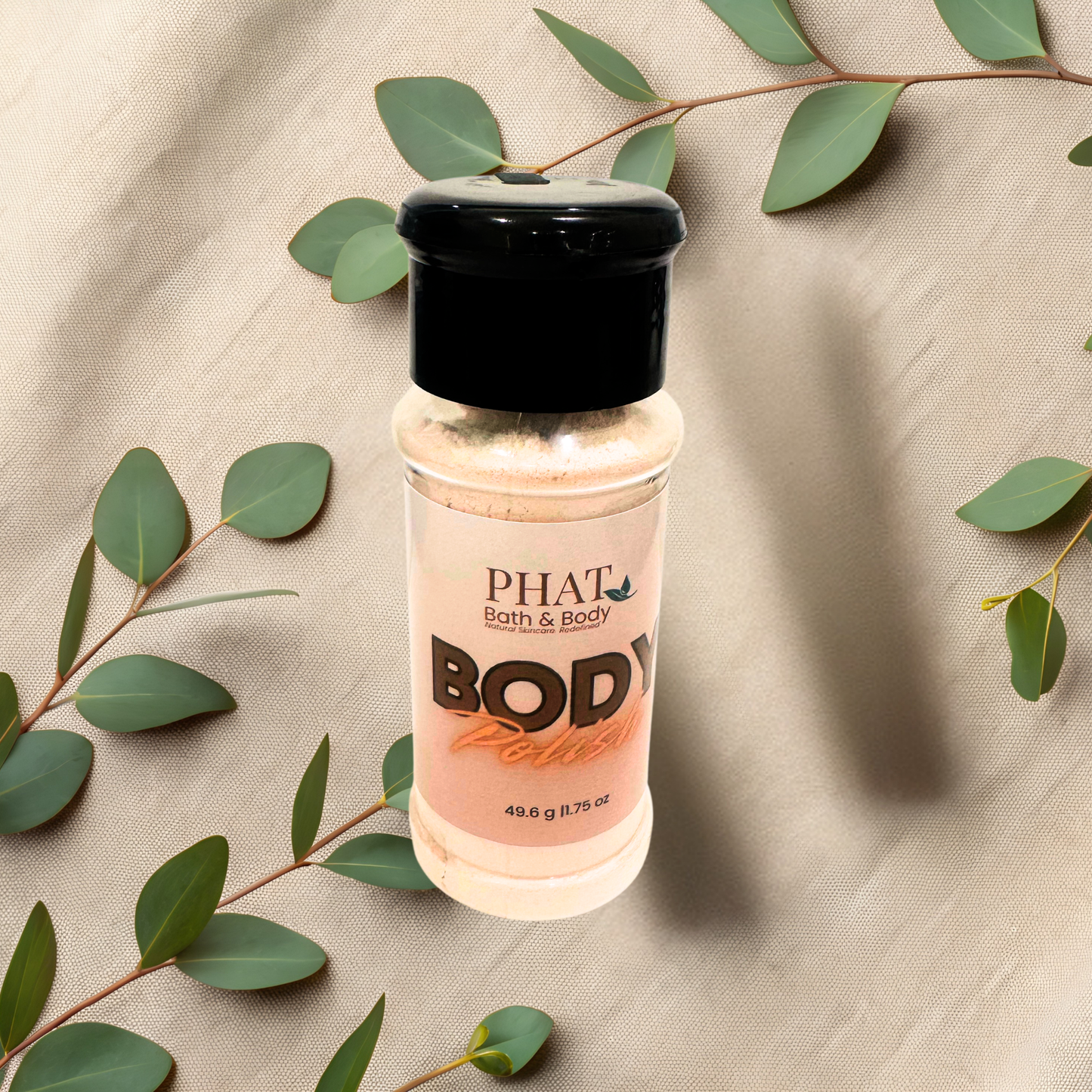 Bottle of 'PHAT Bath & Body' body polish on a textured surface with green leaves.