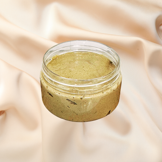 An open clear cosmetic jar filled with a textured olive-green mask, set against a draped beige fabric background.