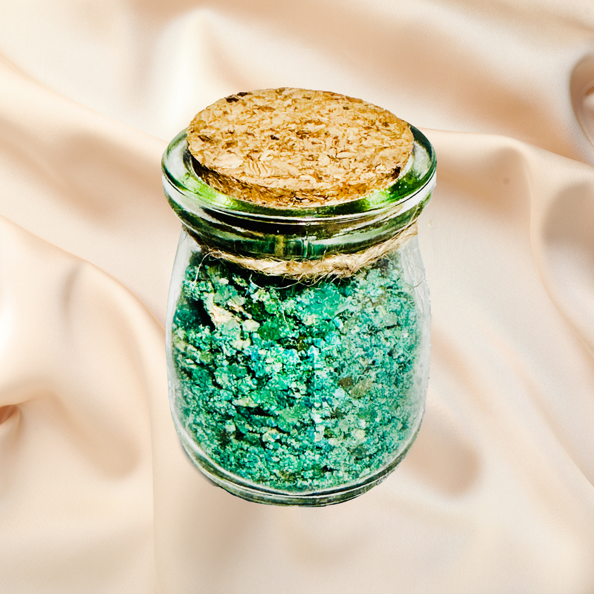 Glass jar with cork lid containing green bath salts on a beige fabric background