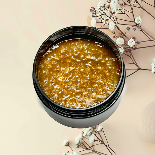 Jar of brown scrub with white flowers on a beige background