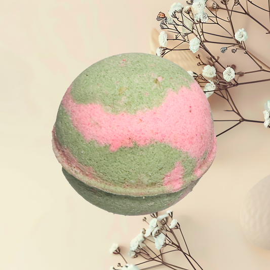 Green and pink bath bomb with dried flowers on a light background