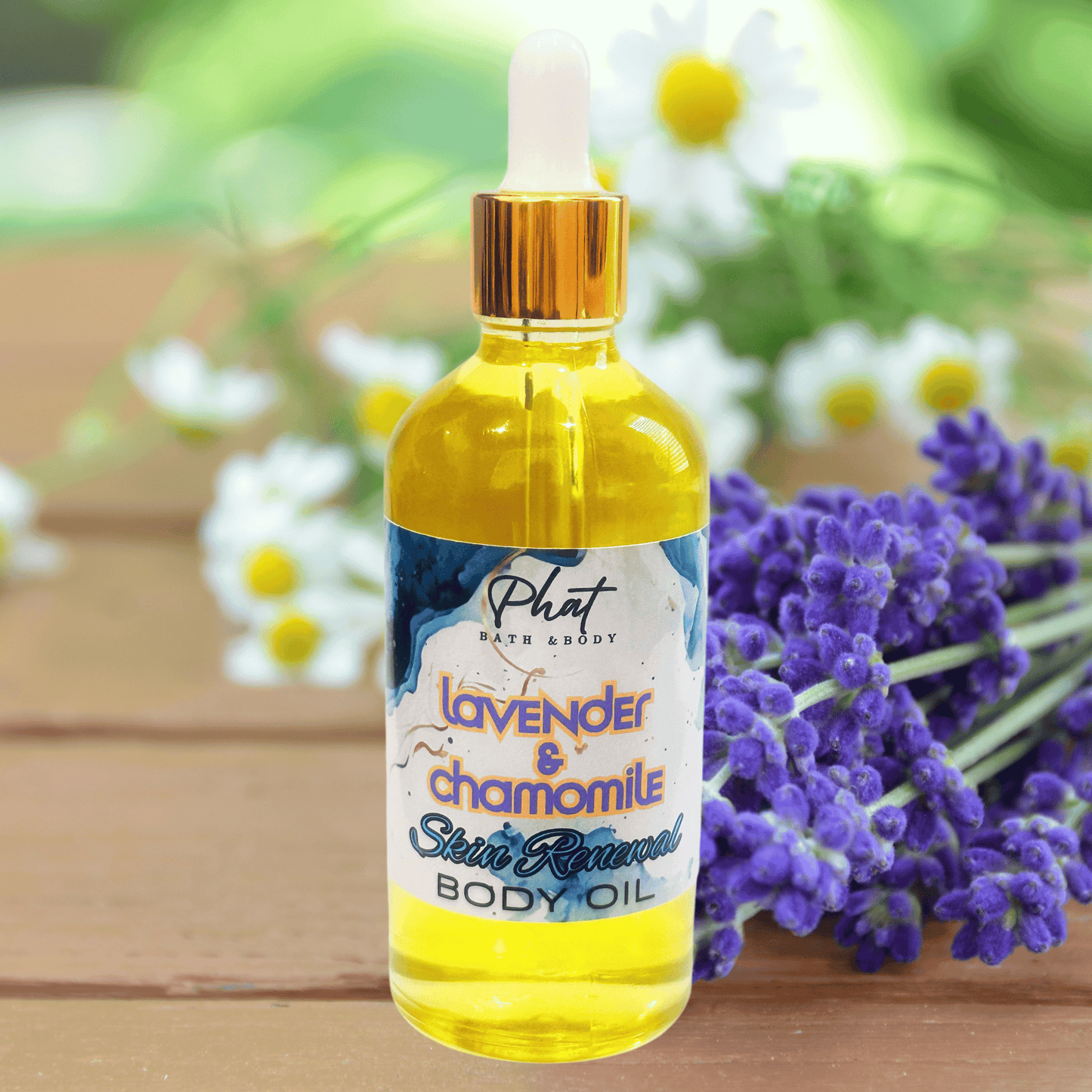 Bottle of lavender and chamomile skin renewal body oil with a label on a wooden surface with flowers in the background.