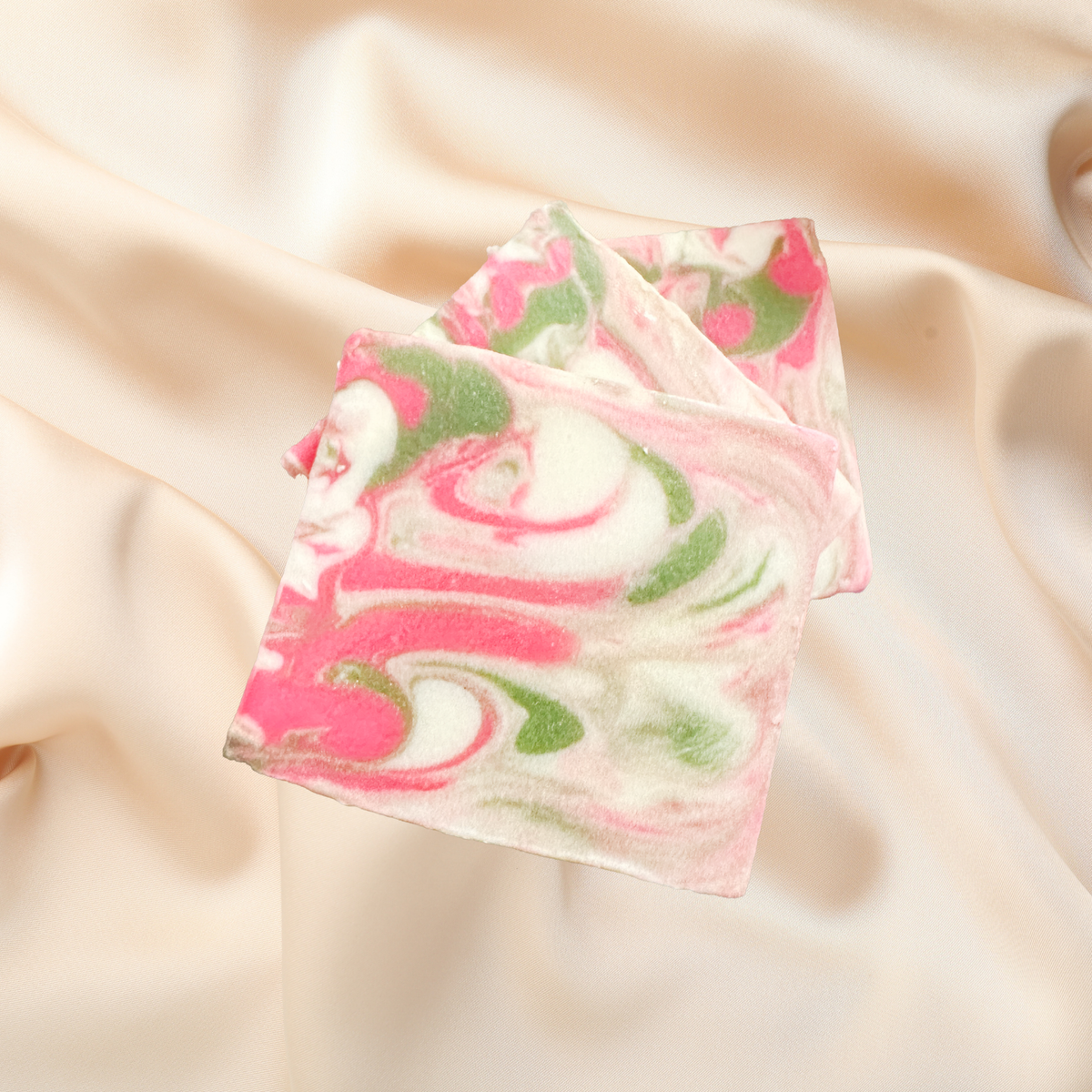 Marbled soap bar with pink and green swirls on a beige fabric background
