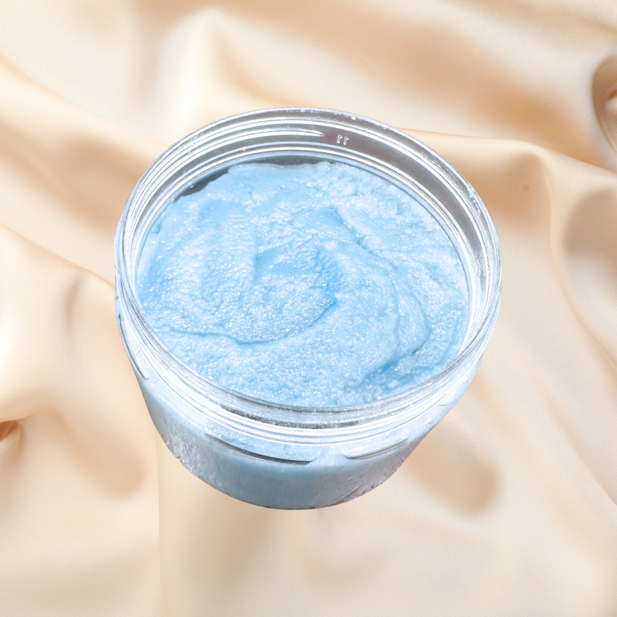 Jar of blue scrub on a beige fabric background