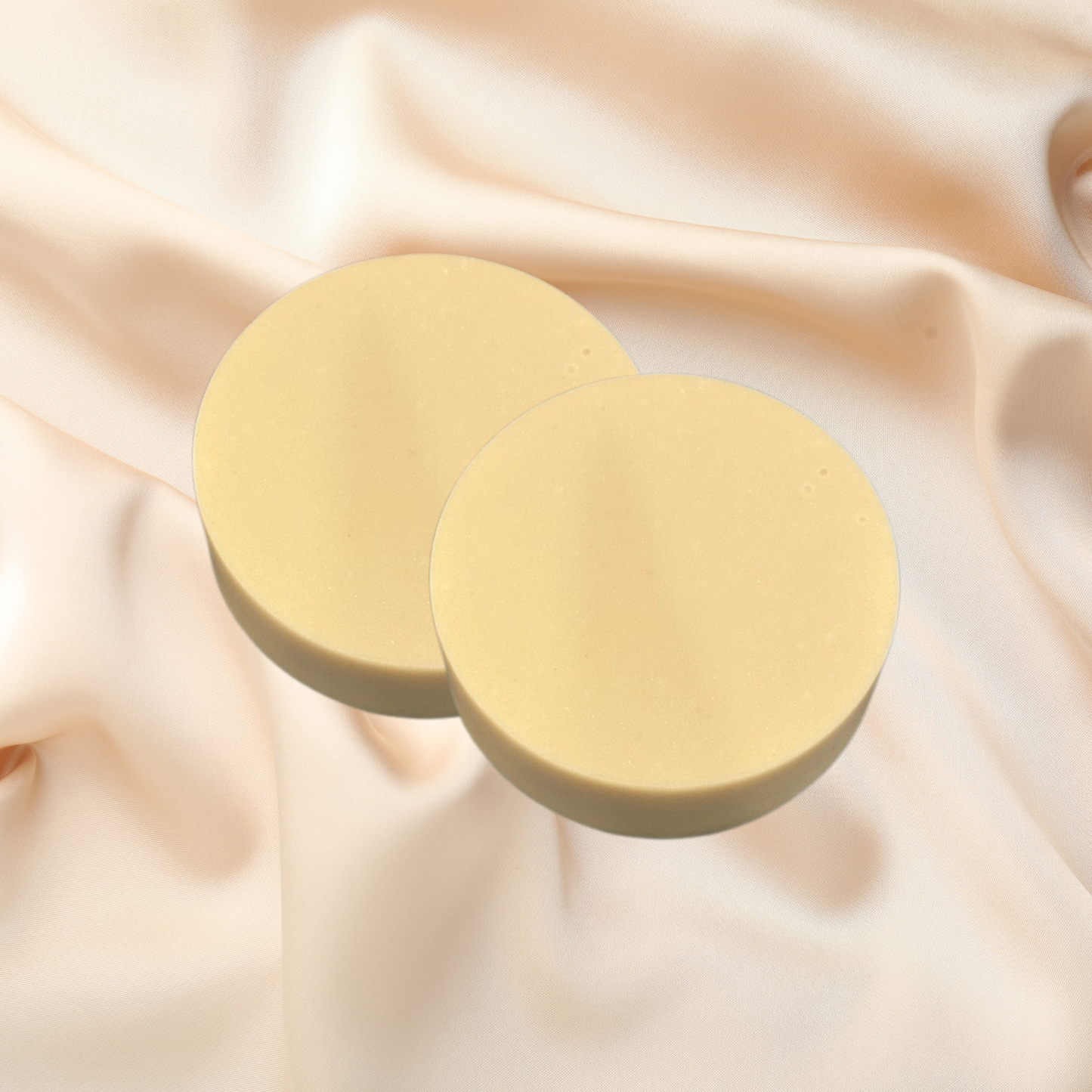 Two gold circular soaps on a beige fabric background