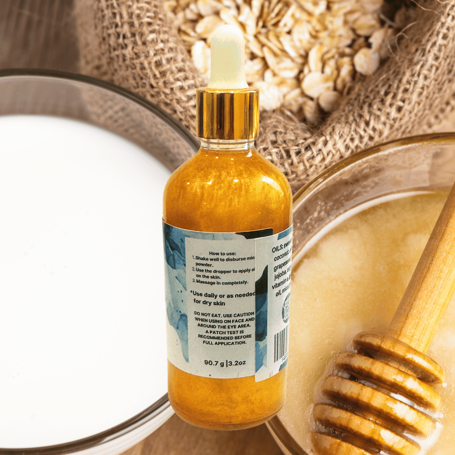 Bottle of milk and honey oil with a dropper on a textured surface with a wooden spoon.