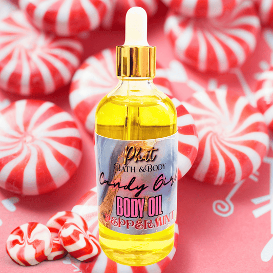 Bottle of candy oil with peppermint scent surrounded by red and white striped candies on a pink background.