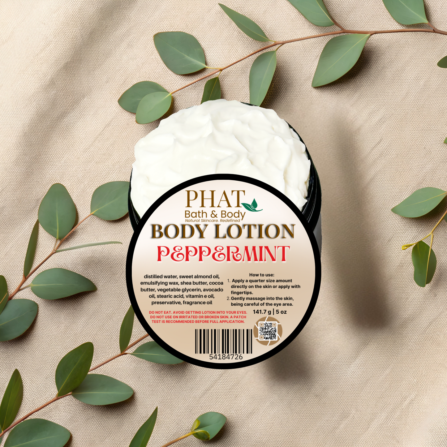 Body lotion container labeled 'Peppermint' by Phat Bath & Body on a beige fabric background with green leaves.