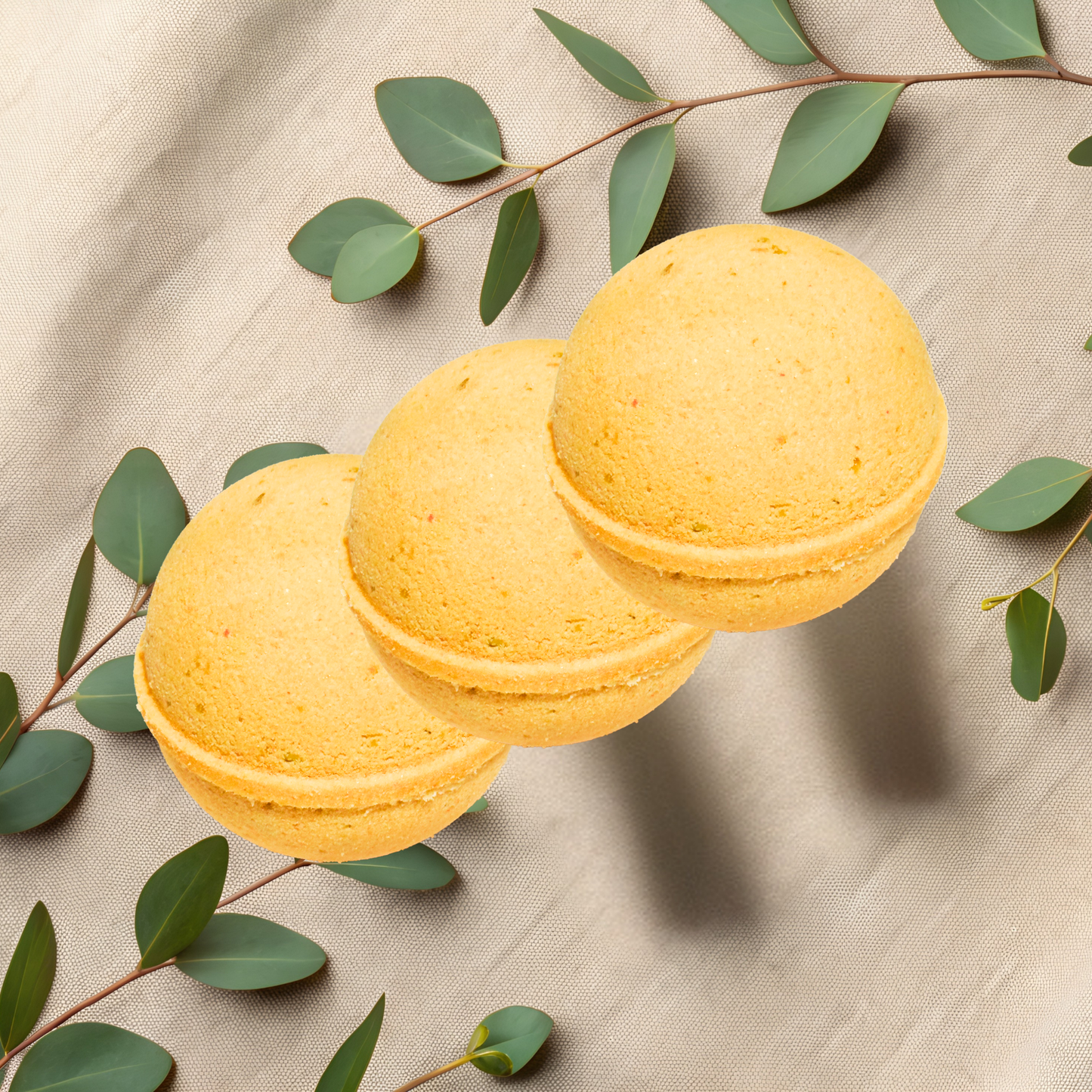 Yellow bath bombs with green leaves on a beige fabric background