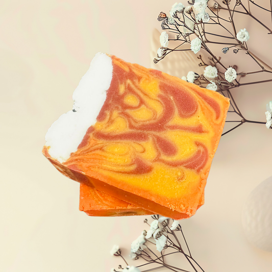Swirled orange and yellow soap bar with white flowers and branches on a beige background