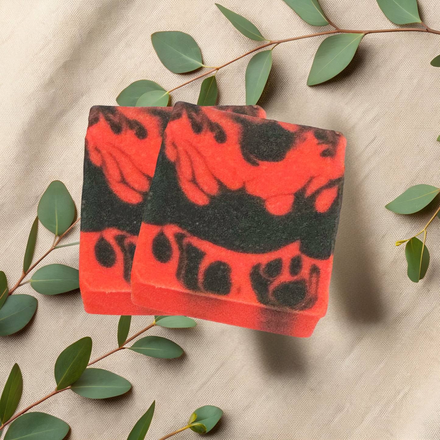 Red and black soap bars with leafy branches on a beige fabric background