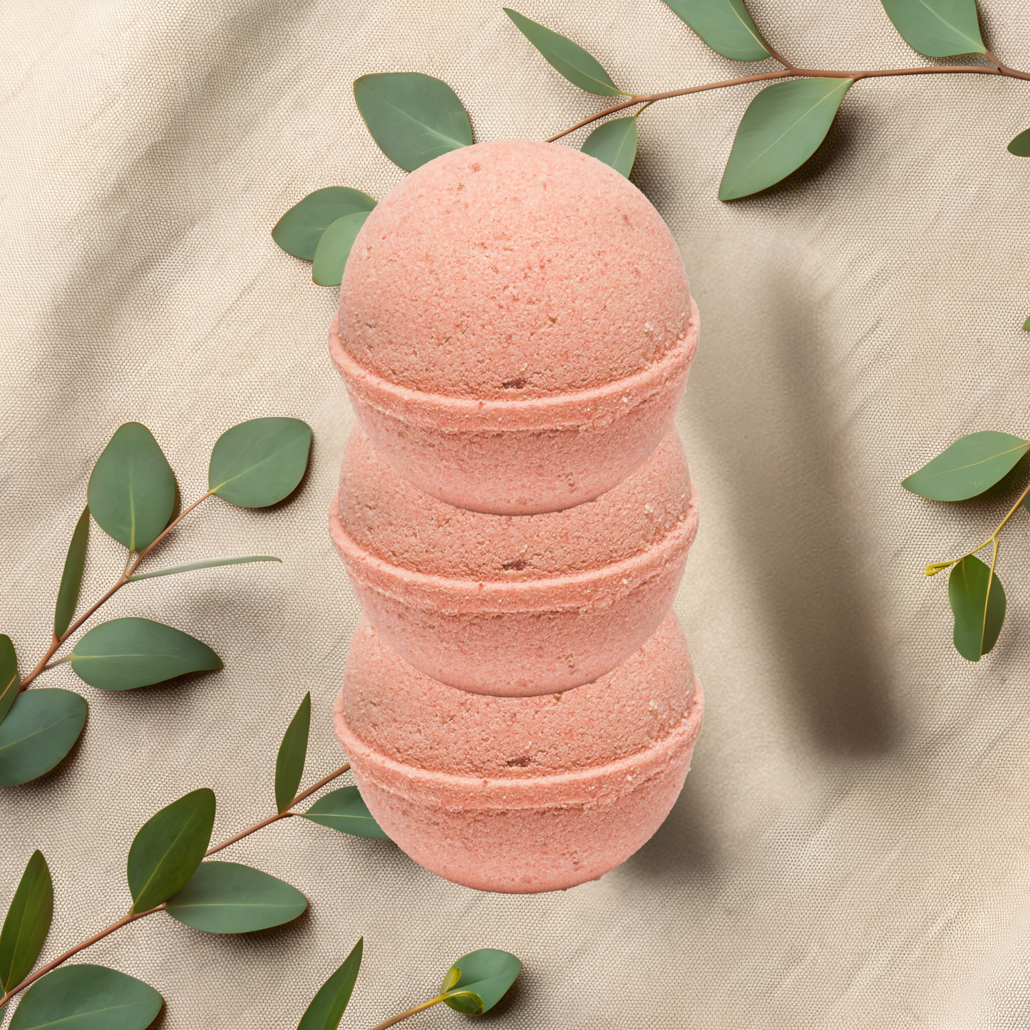 Pink bath bomb with green leaves on a beige fabric background