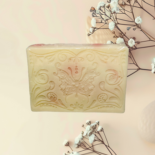 Decorative soap bar with intricate design on a light pink background with small white flowers.