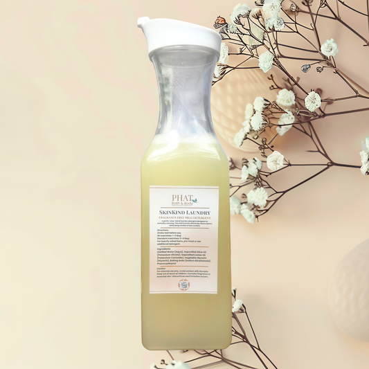 Bottle of Skinkind Laundry detergent with a label, set against a neutral background with white flowers.