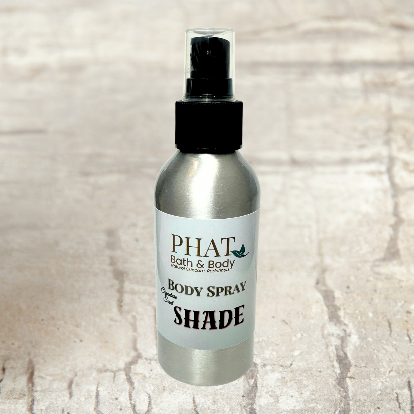 Body spray bottle labeled 'PHAT Bath & Body' on a textured beige background