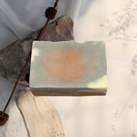 Bar of soap with natural elements on a textured surface