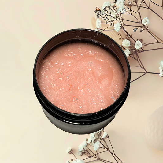 Pink sugar scrub in a black jar with white flowers on a beige background