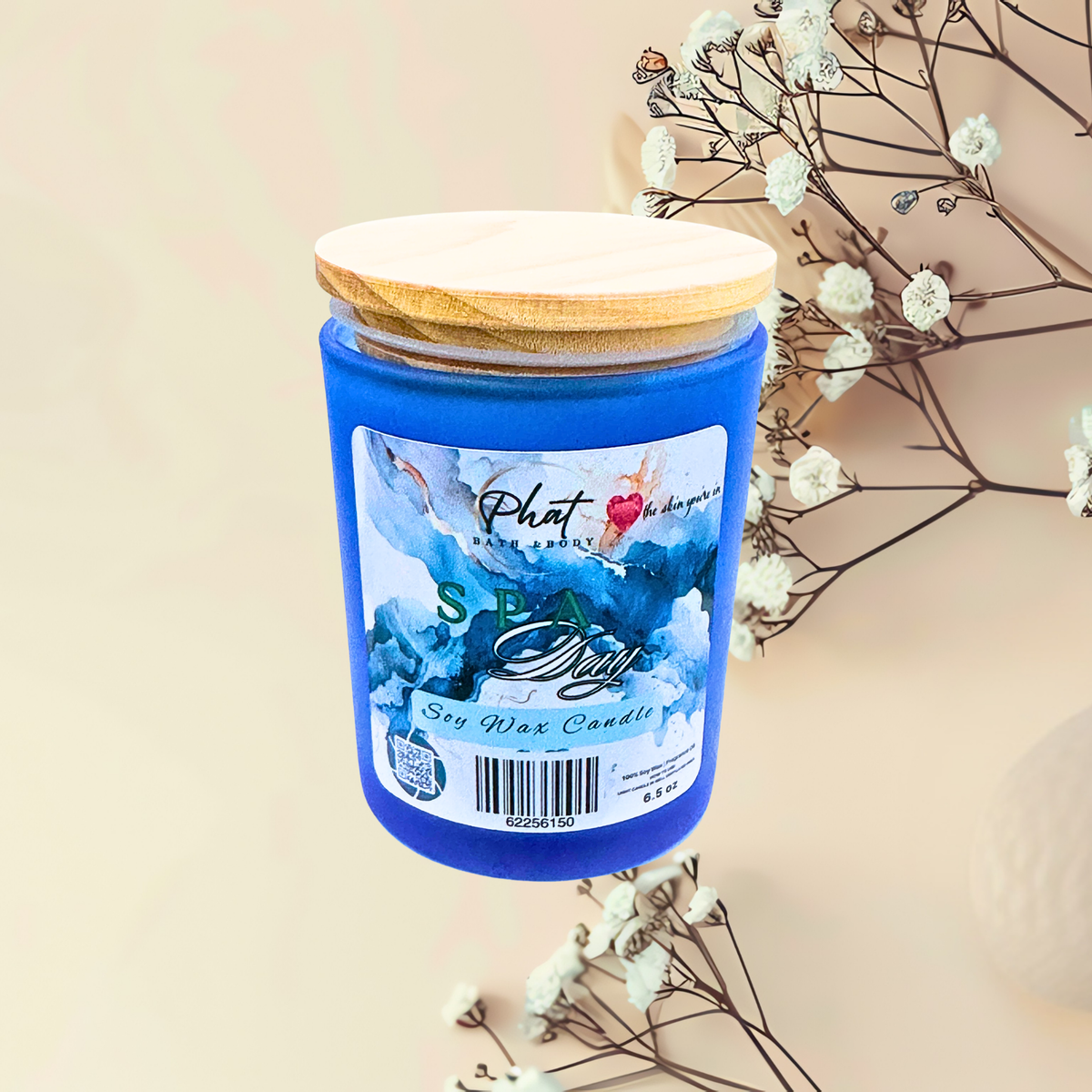 Blue candle with wooden lid on a beige background with white flowers