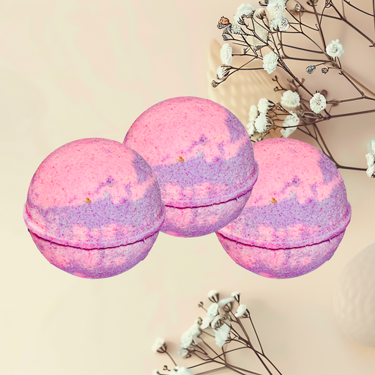 Three pink and purple bath bombs with white flowers on a beige background