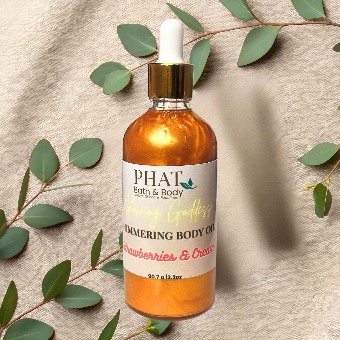 Bottle of PHAT Bath & Body body oil with a dropper on a beige fabric background with green leaves.