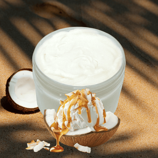 Jar of white cream on a coconut, surrounded by coconut pieces on a sandy background.