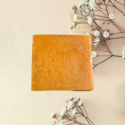 Bar of soap on a light pink background with dried flowers
