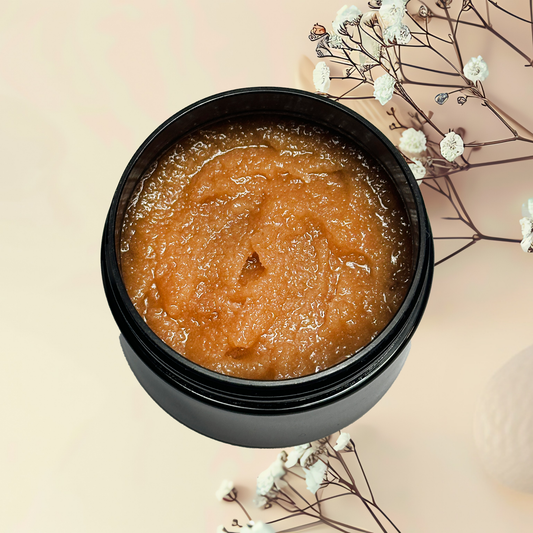 Black container of brown scrub with flowers on a beige background