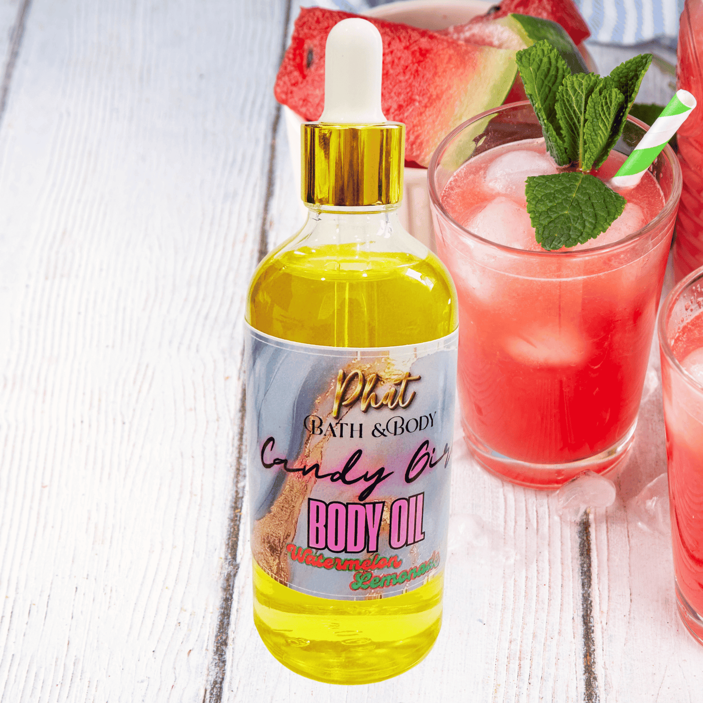 Bottle of body oil with a dropper next to a glass of pink lemonade on a wooden surface.