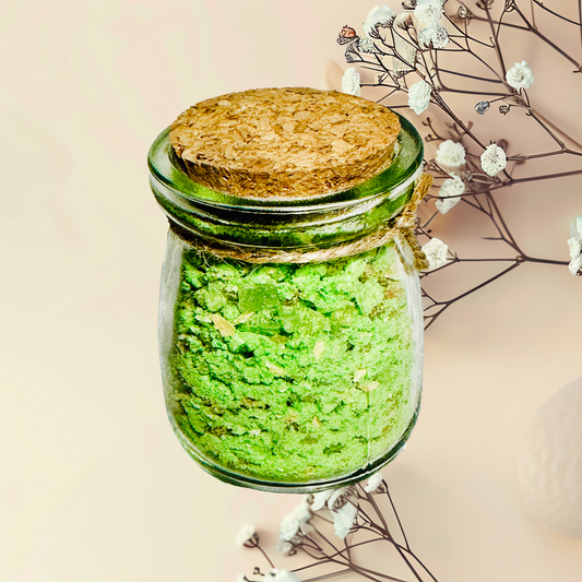 Glass jar with green bath salts and cork lid on a light background