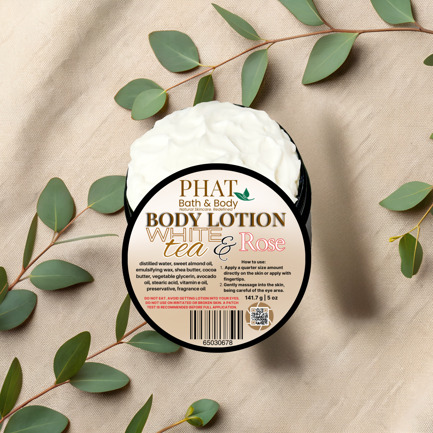 Body lotion container with 'Phat Bath & Body' label on a beige fabric background with green leaves.