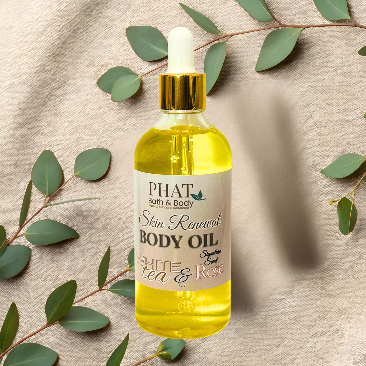 Bottle of Phat Bath & Body body oil with a dropper on a beige fabric background with green leaves.